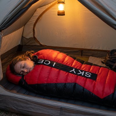 Femme dans sa tente avec sont Sac de couchage pour grand froid 