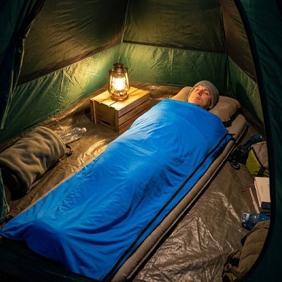 Homme dans sont Sac de couchage bleu dans une tente